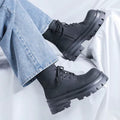 Bottines noires à plateforme pour homme portées avec un jean bleu, vue de profil montrant les lacets noirs et les semelles épaisses crantées.