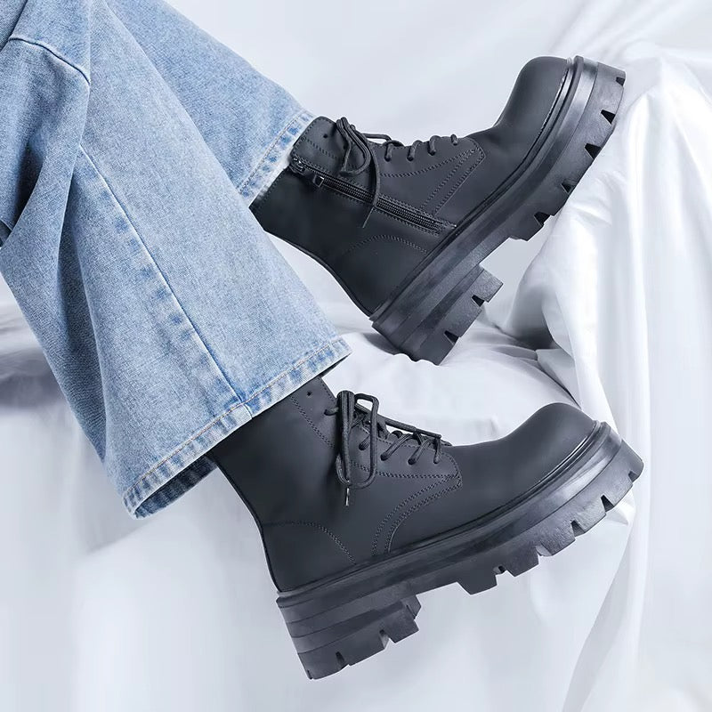 Bottines noires à plateforme pour homme portées avec un jean bleu, vue de profil montrant les lacets noirs et les semelles épaisses crantées.