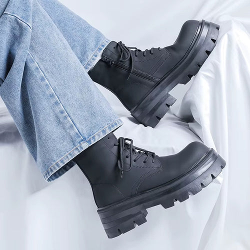 Bottines noires à plateforme pour homme portées avec un jean bleu, vue de profil montrant les lacets noirs et les semelles épaisses crantées.