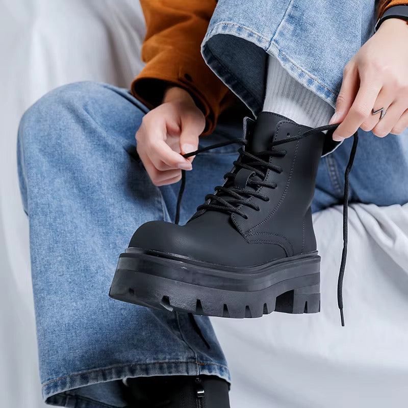 Bottine noire montante à plateforme pour homme, portée avec un jean bleu, avec lacets en cours d'ajustement et semelle épaisse crantée.