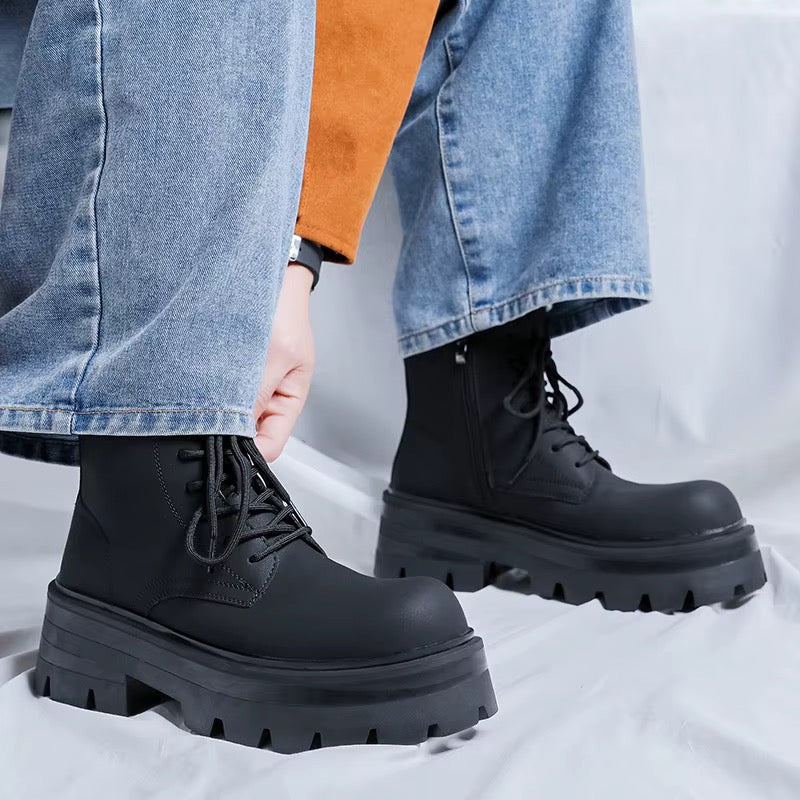Bottines noires montantes à lacets pour homme, avec semelles épaisses crantées, portées avec un jean bleu.
