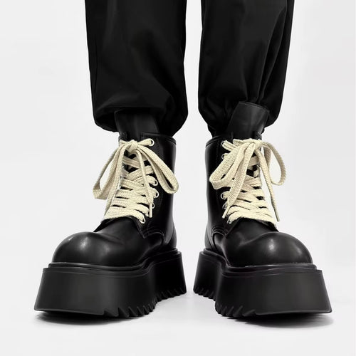 Bottines d’hiver noires pour homme portées de face, avec lacets crème contrastants, semelles épaisses à plateforme et bouts arrondis.