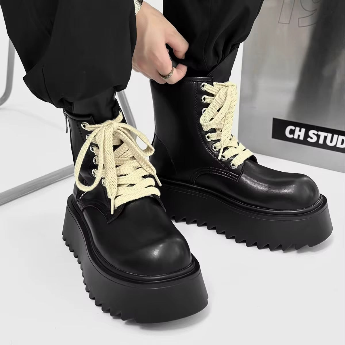 Bottines d’hiver noires pour homme portées avec un pantalon noir, lacets crème contrastants et semelles épaisses à plateforme crantée.
